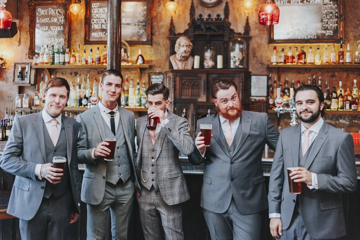 Groom and his groomsmen standing at the bar in The Old Queens Head Pub, looking at their Islington Town Hall Wedding Photographer