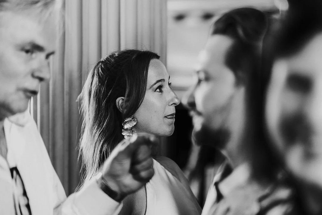 A Black & White Image of a guest in the background slightly poking her tongue at a Hampton Court House Wedding.