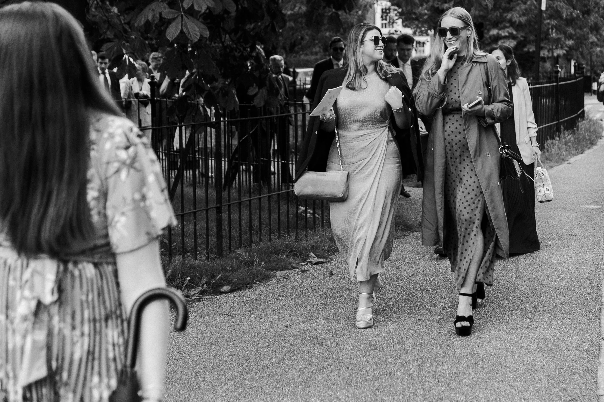 Wedding guests talking and walking down the street towards wedding reception at a Highgate, London Wedding
