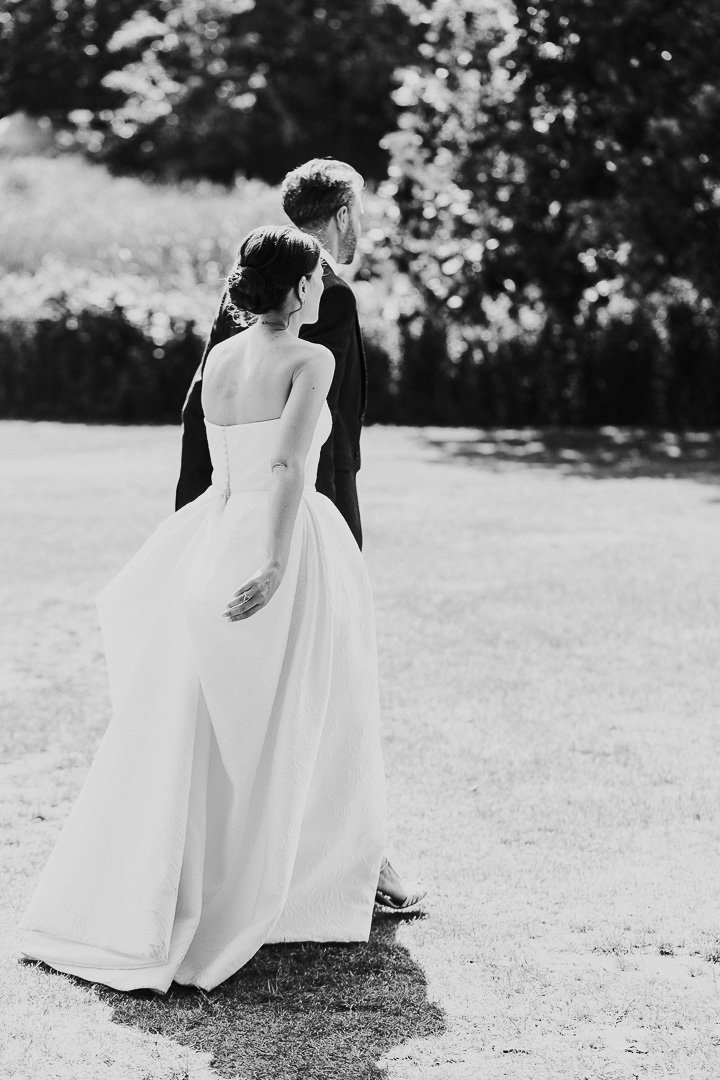 Bride & Groom walking away from the camera in Hampton Court House's gardens at a London Weddding.