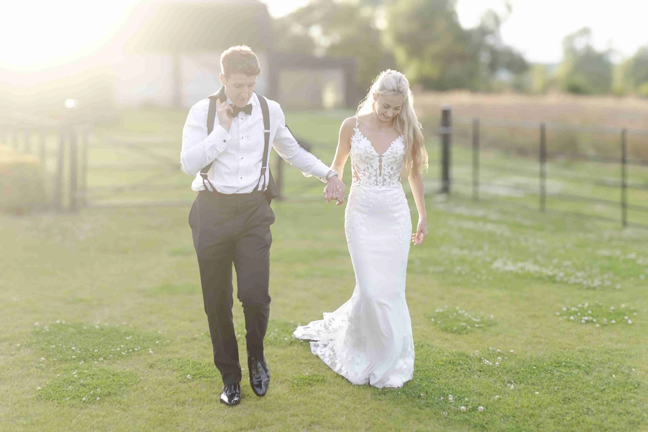 Couple walking hand in hand while the groom has his jacket sling over his shoulder at the Halfmoon Farm Wedding in Rutland