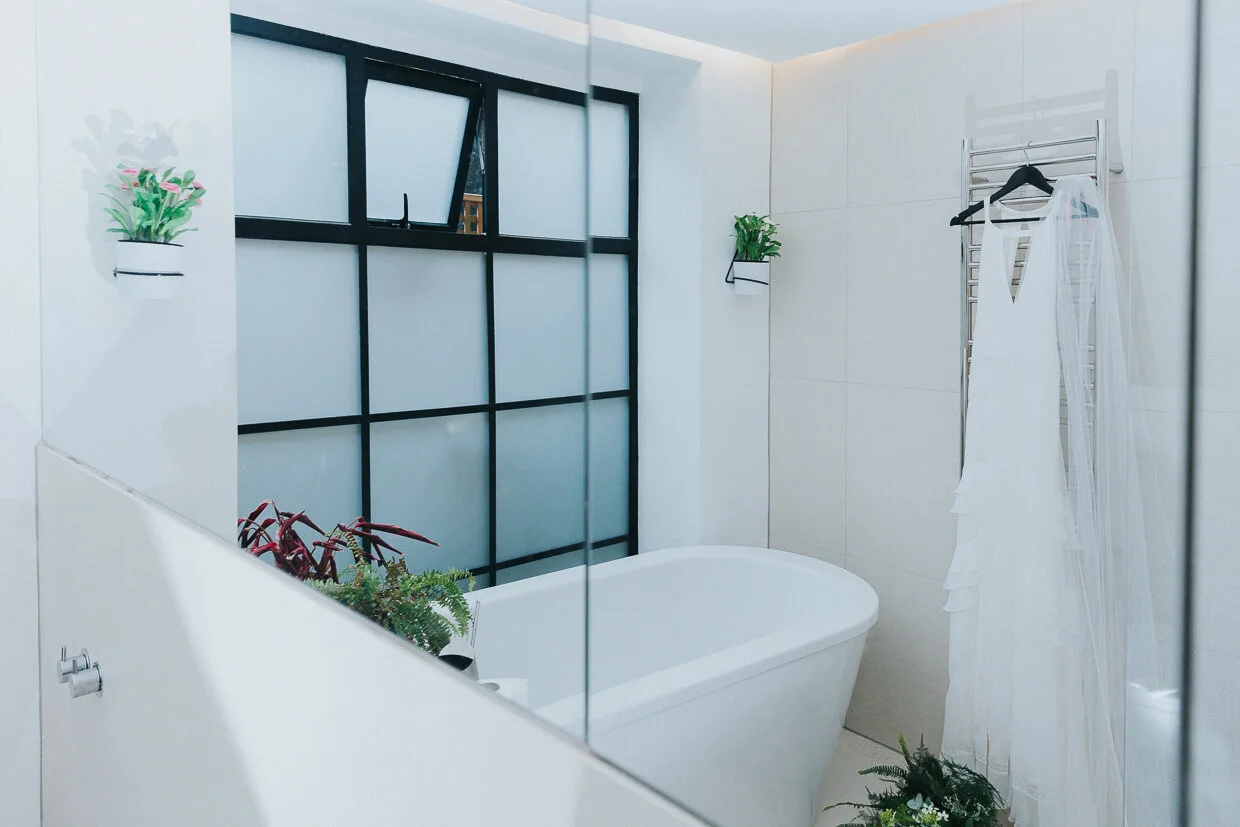 Wedding Dress hanging in a light bathroom at a City of London Wedding