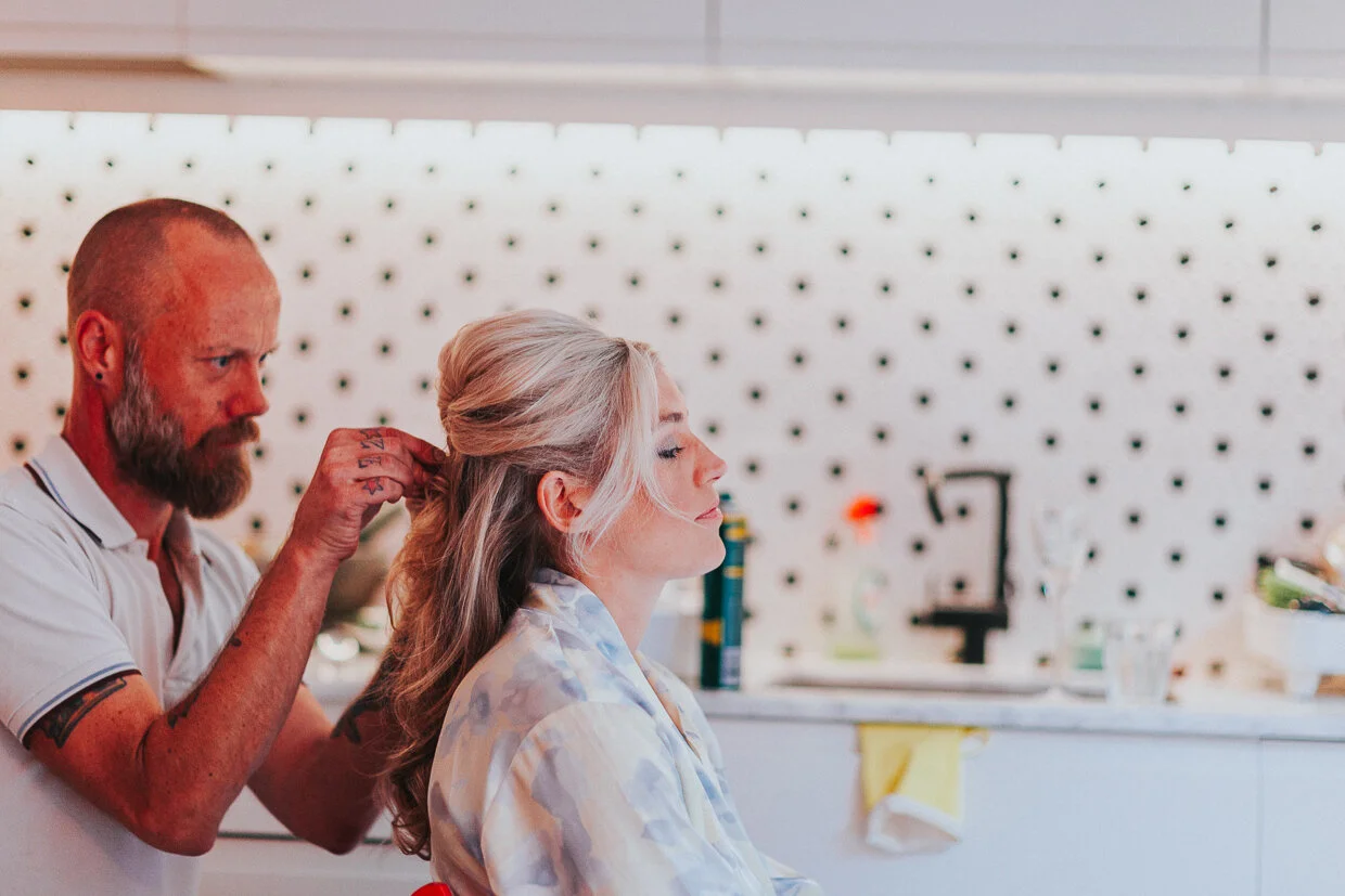 Bride getting the final touches to her hair by a hair stylist at morning prep at a City of London Wedding.
