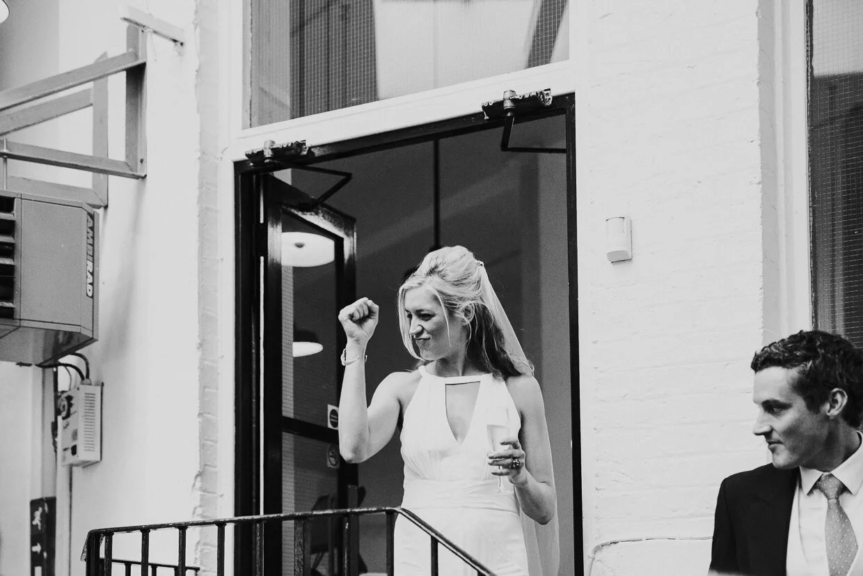 Bride entering the reception dinner with a fist pump at the guests at St John Restaurant, Smithfield at a City of London Wedding.