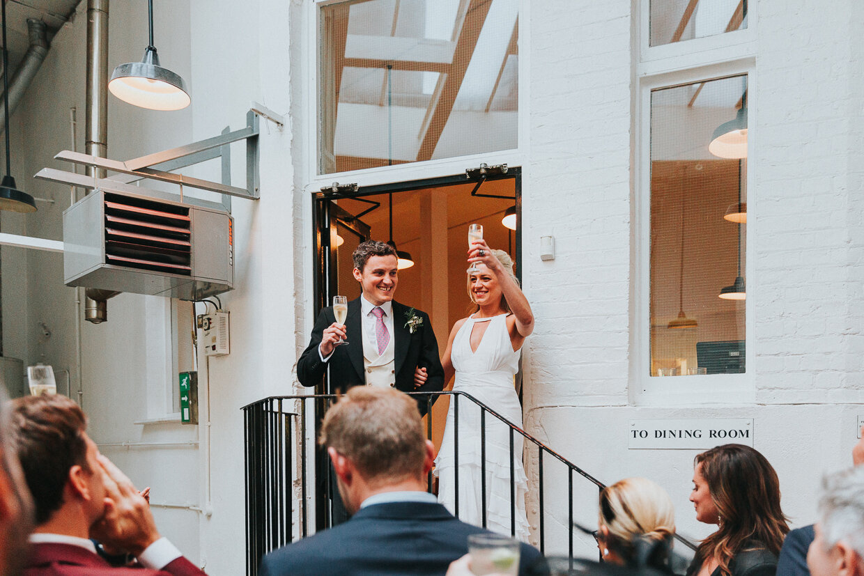 Wedding couple on the top step toasting the reception room at St John Restaurant, Smithfield at a City of London Wedding