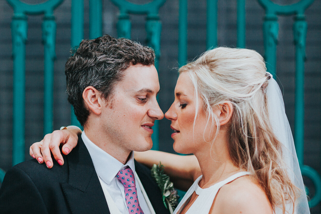 Wedding couple standing and looking at each other very close next to metal gates at Smithfield Market, for a City of London Wedding.