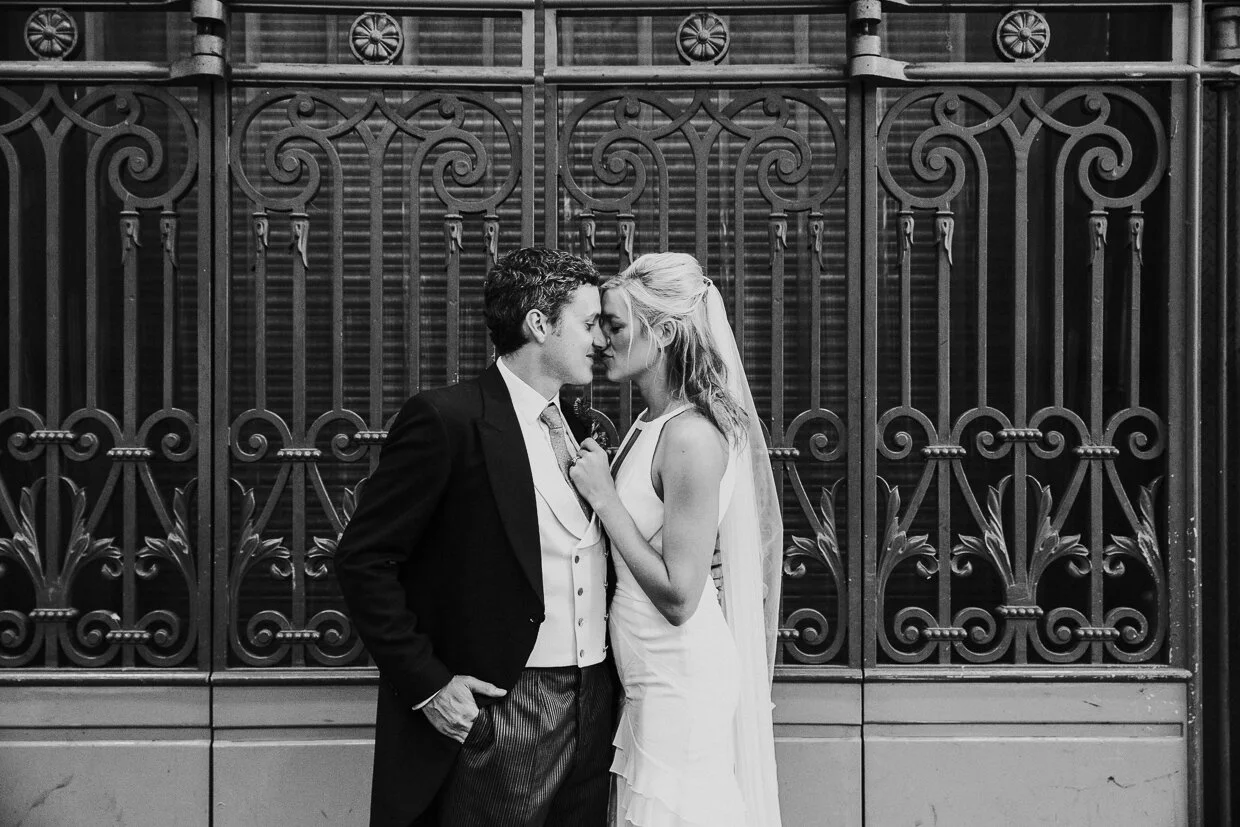 A wedding couple in an embracing hold next to Metal gates in Smithfield Market for a City of London Wedding.