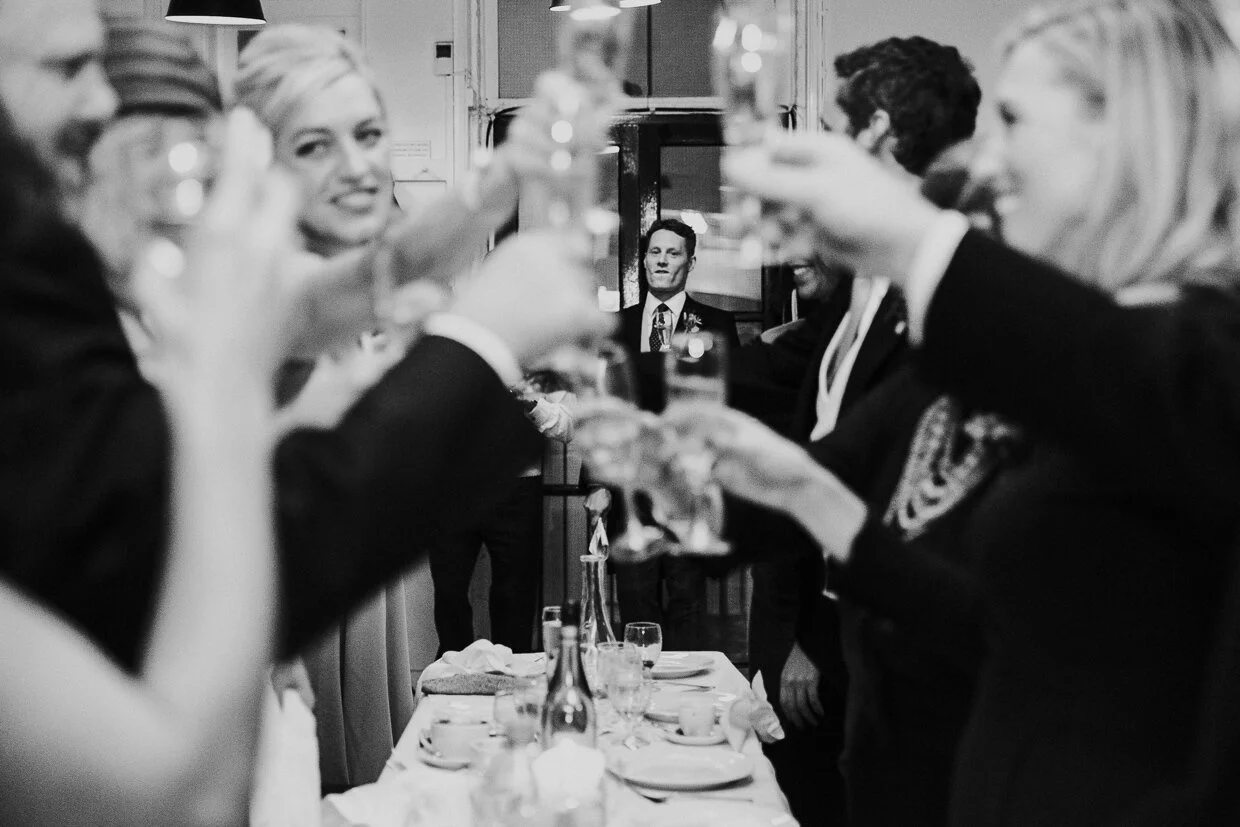 Guest standing at the end of the table after speech, with Wedding guests toasting each other across the table at St John Restaurant, Smithfield at a City of London Wedding