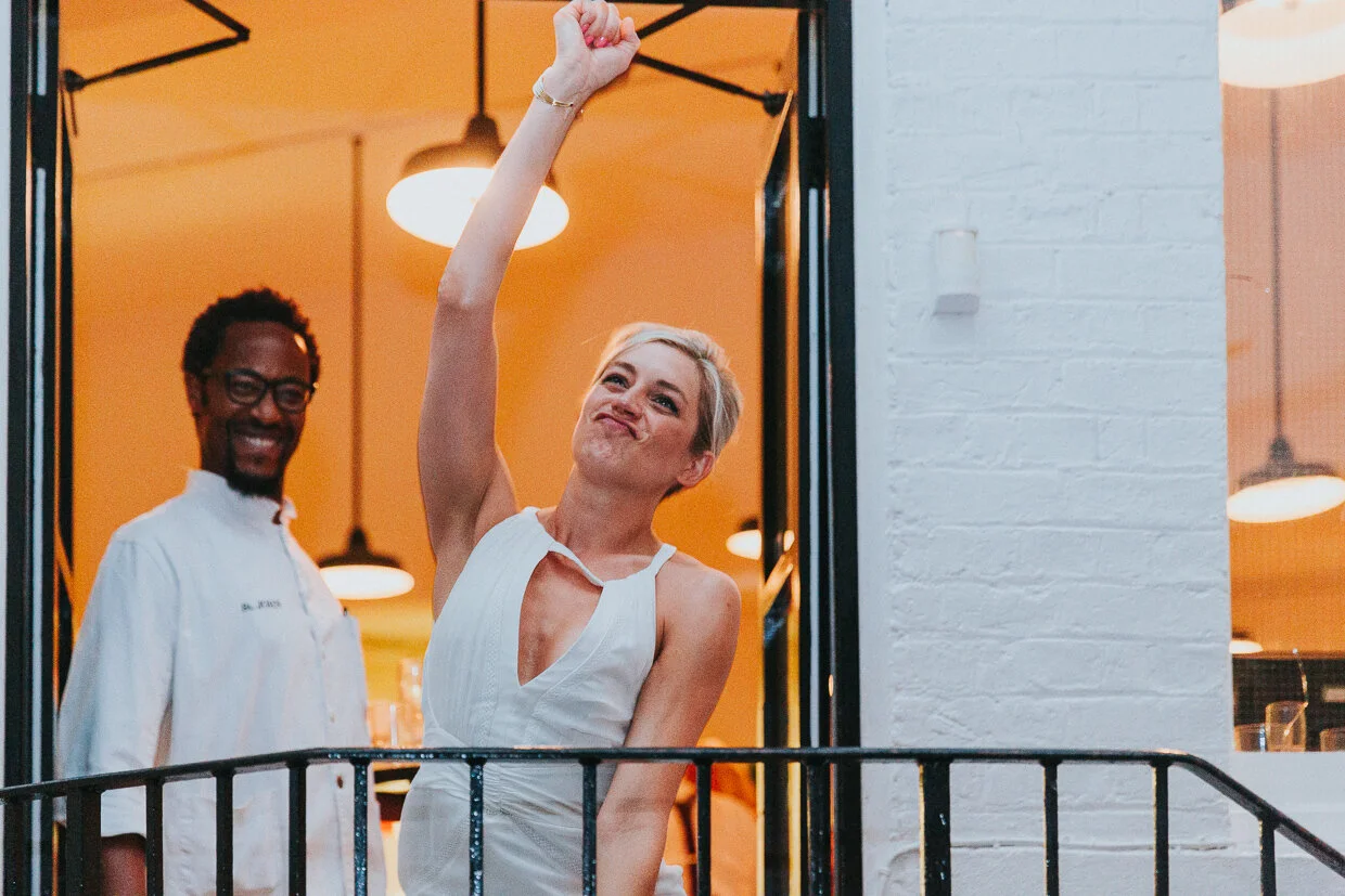 Bride at the top of the stairway dancing with a chef behind smiling at St John Restaurant, Smithfield for a City of London Wedding.