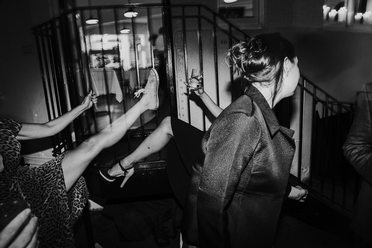 Wedding guests on the dance floor with arms and legs in the air while a guest walks past at St Johns Restaurant, City of London Wedding