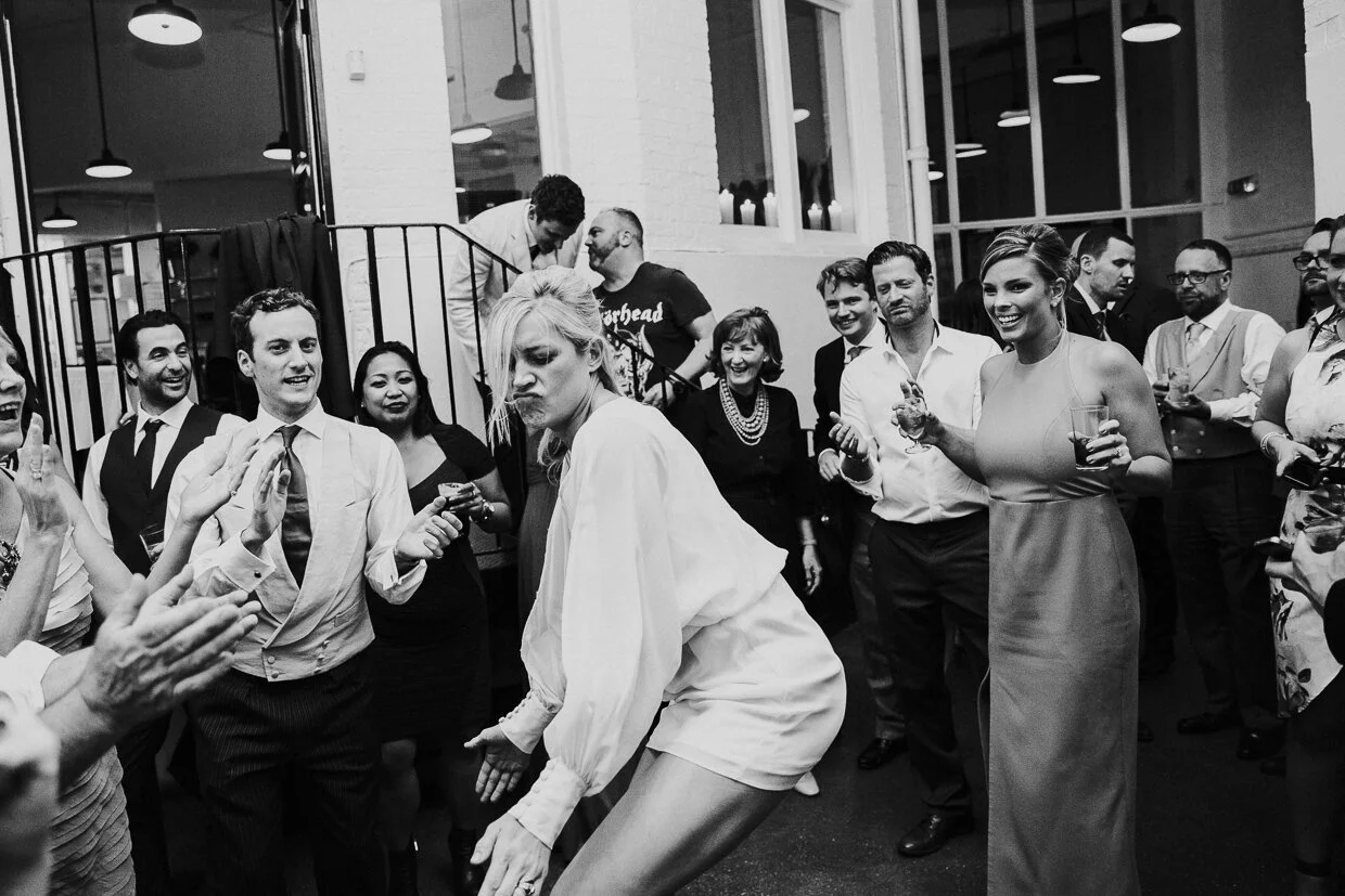 People dancing and socializing at a party or celebration, some holding drinks, with happy and engaged expressions.