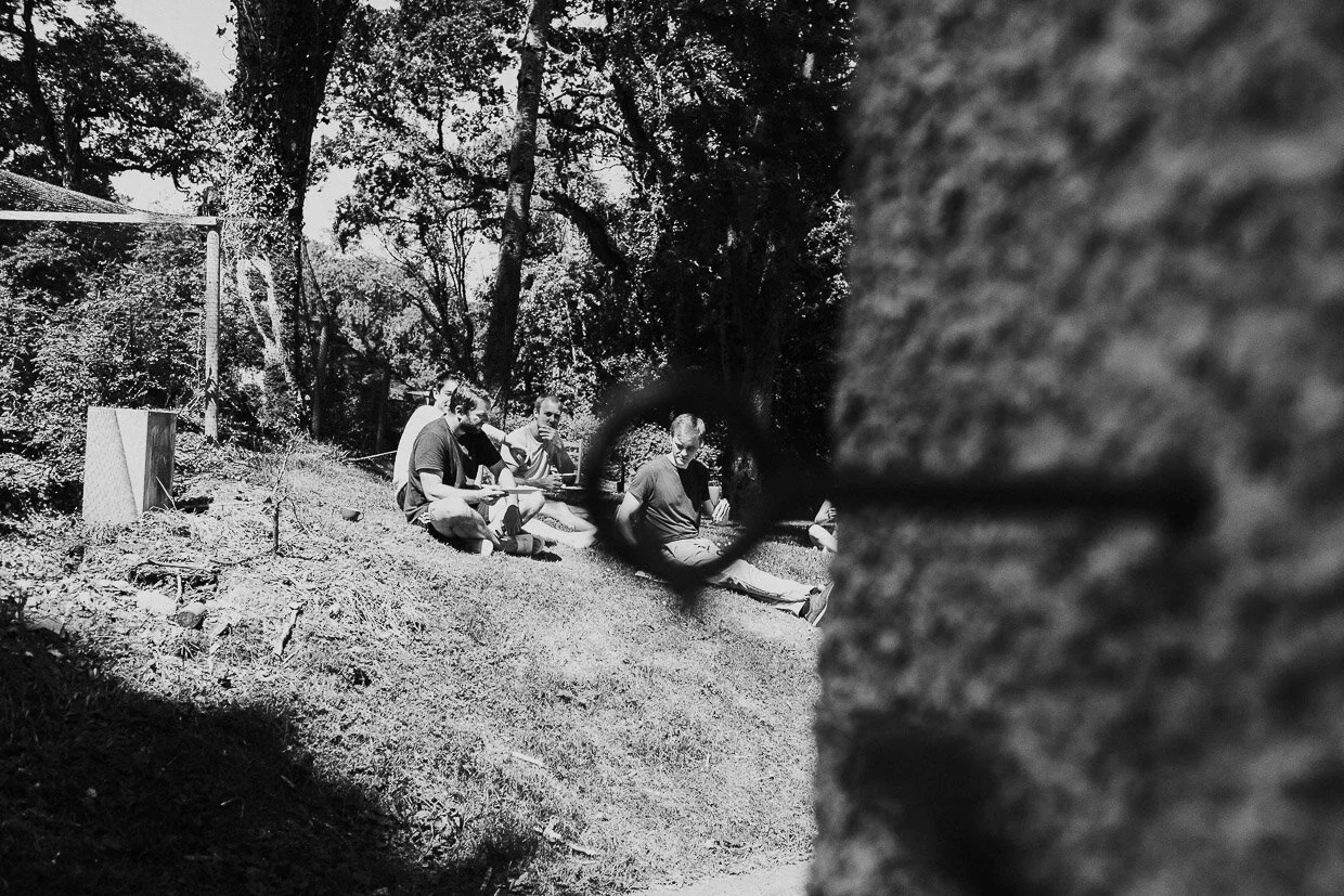 Groom party sitting on the hill side outside a cottage on the Ballynatray Estate for a Cork Wedding