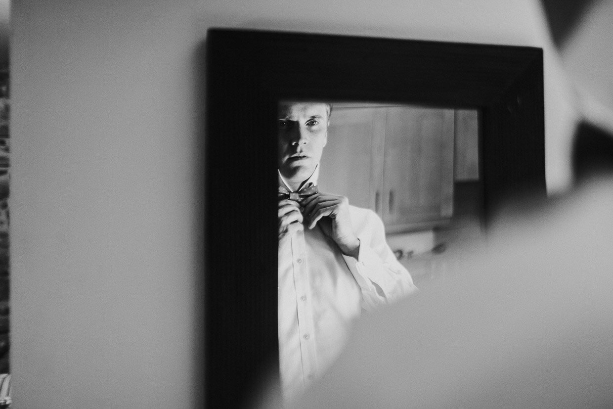Reflection of Groom in the mirror tying his bow-tie on the Ballynatray Estate for a Cork Wedding