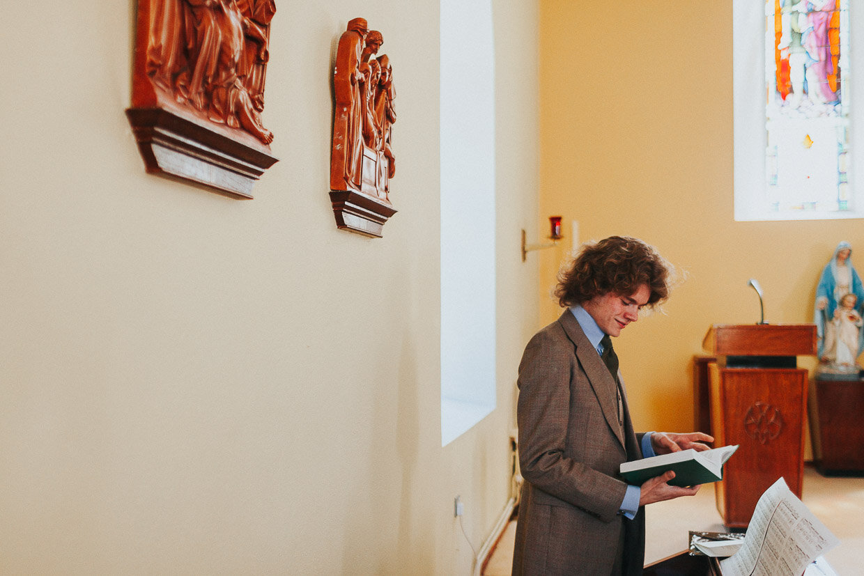 Organist reading a book inside the church before the ceremony on the Ballynatray Estate for a Cork Wedding