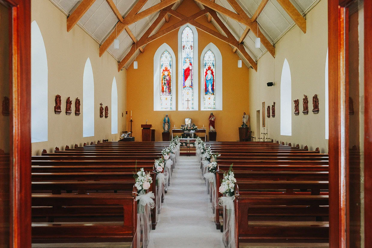 Empty church before the ceremony with flowers arrangement down aisle on the Ballynatray Estate for a Cork Wedding