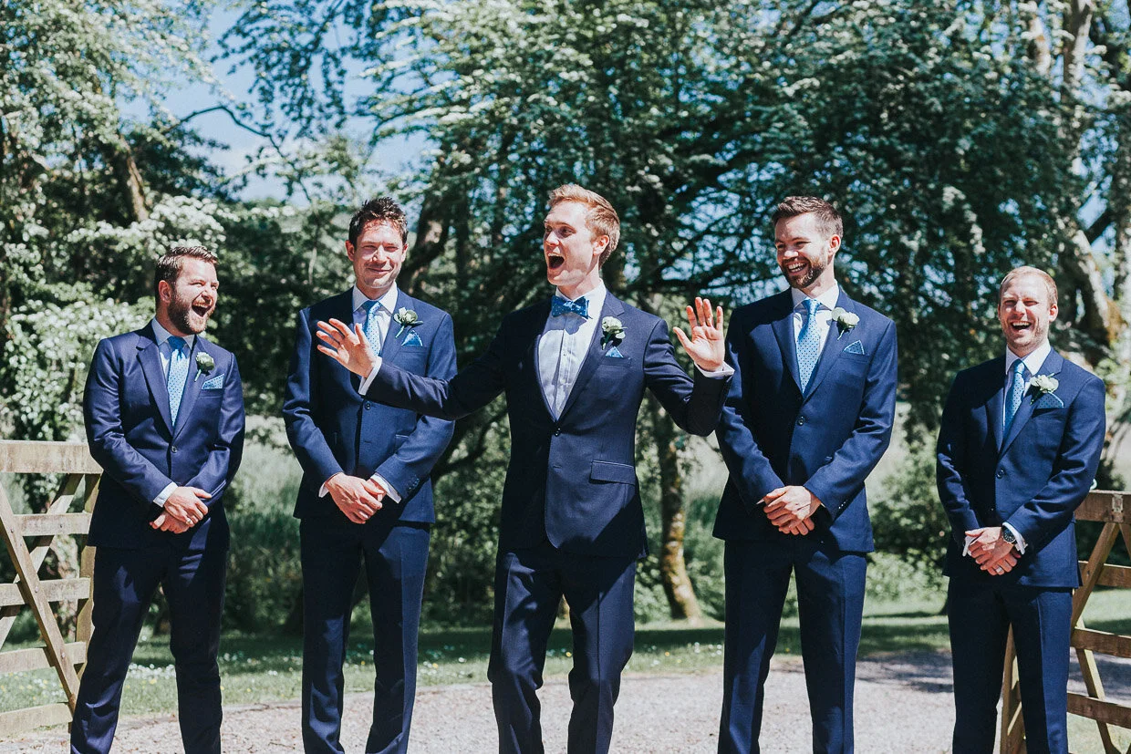 Groom laughing at front of the group shot of Groomsmen on the Ballynatray Estate for a Cork Wedding