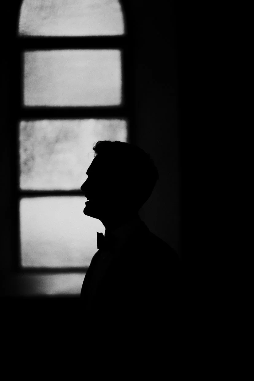Silhouette of the groom standing in front of a window in the church on the Ballynatray Estate for a Cork Wedding