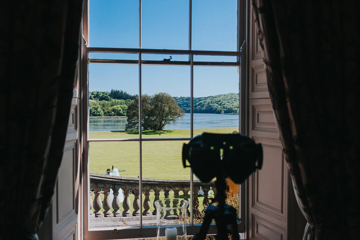 View of the lake from the house through a window with a set of binoculars on a tripod on the Ballynatray Estate for a Cork Wedding