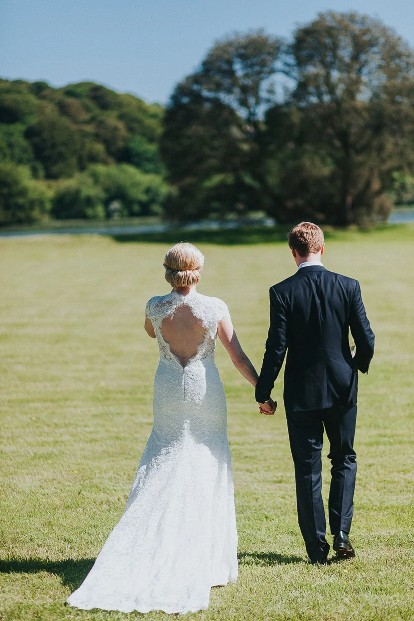 Wedding couple walking hand in hand away from the house across the grounds on the Ballynatray Estate for a Cork Wedding