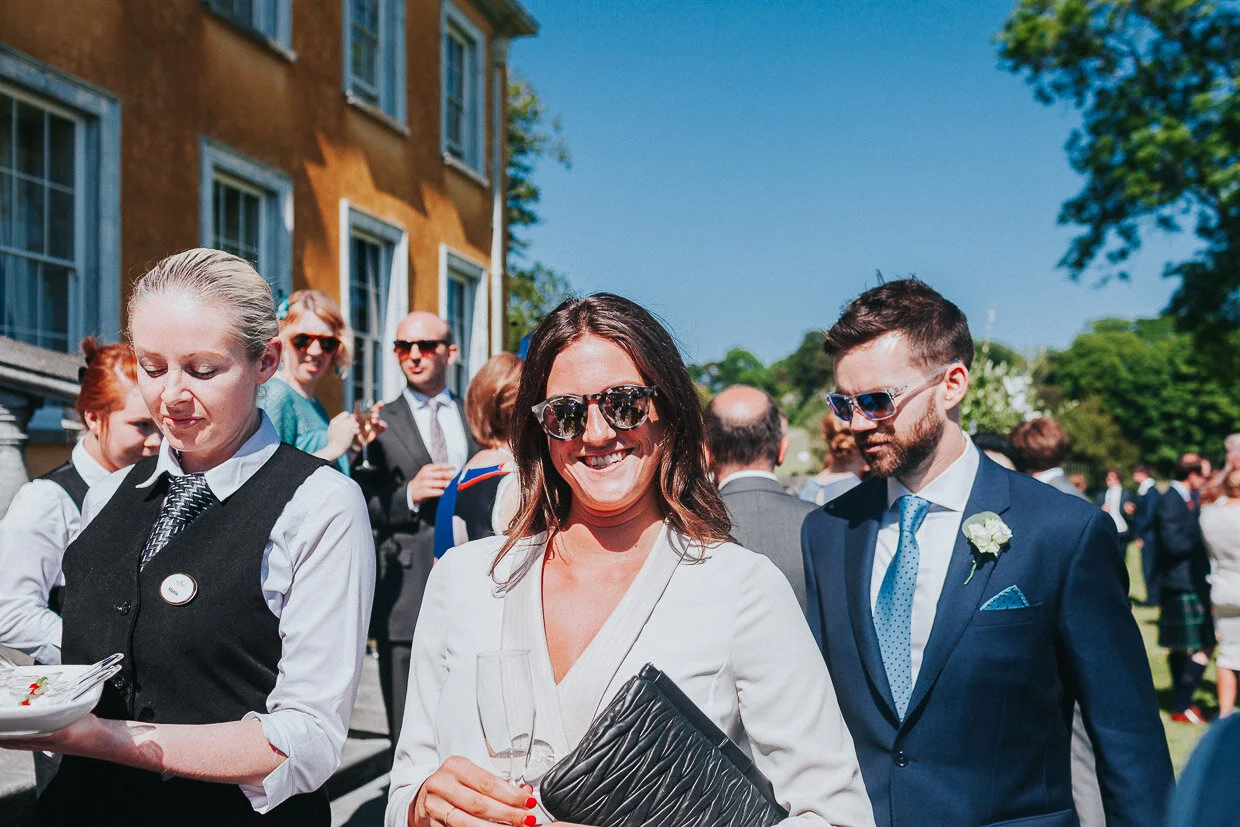 Wedding guests wearing sunglasses smiling at the camera during the drinks reception on the Ballynatray Estate for a Cork Wedding