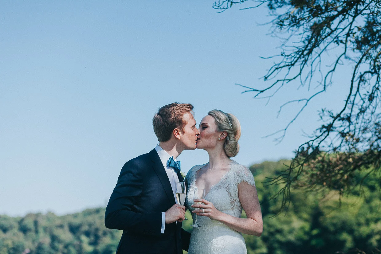 Wedding couple kissing holding drinks on the grounds on the Ballynatray Estate for a Cork Wedding