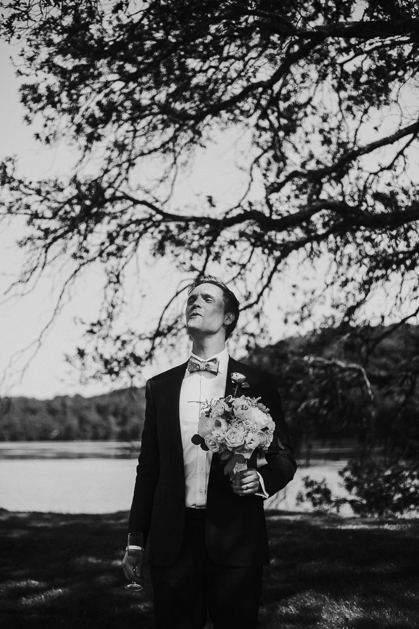Groom holding the Bouquet standing alone under a tree on the Ballynatray Estate for a Cork Wedding