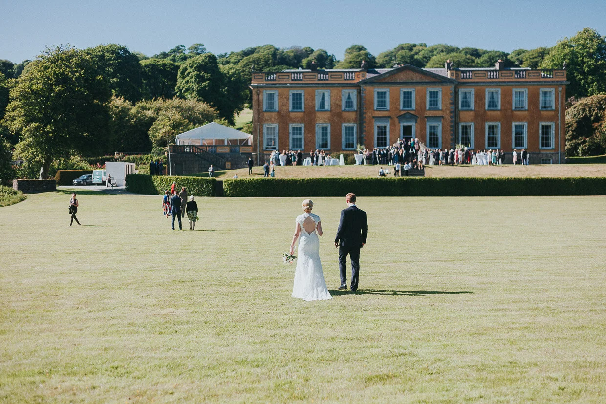 Wedding couple walking back to the house across the grounds on the Ballynatray Estate for a Cork Wedding