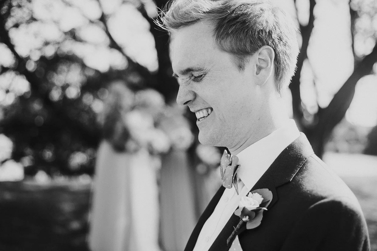 Grooom with eyes closed laughing while bridal party in the background on the Ballynatray Estate for a Cork Wedding