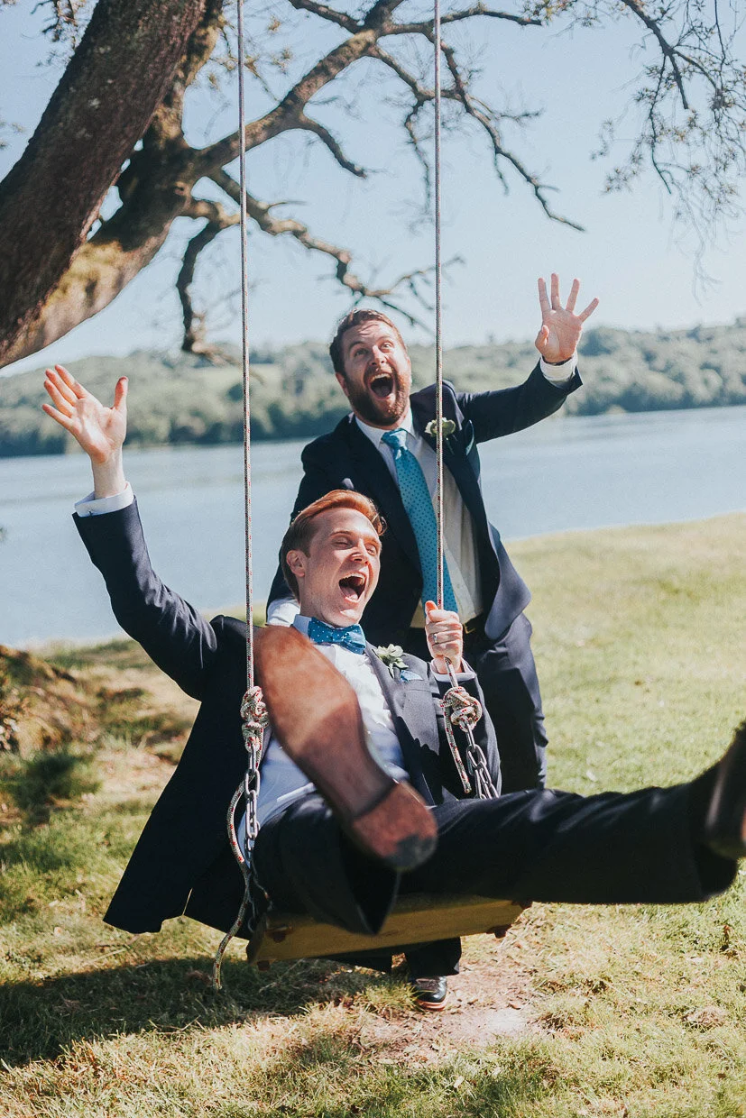 Bestman pushing the Groom on a wooden swing attached to a tree, both laughing on the Ballynatray Estate for a Cork Wedding