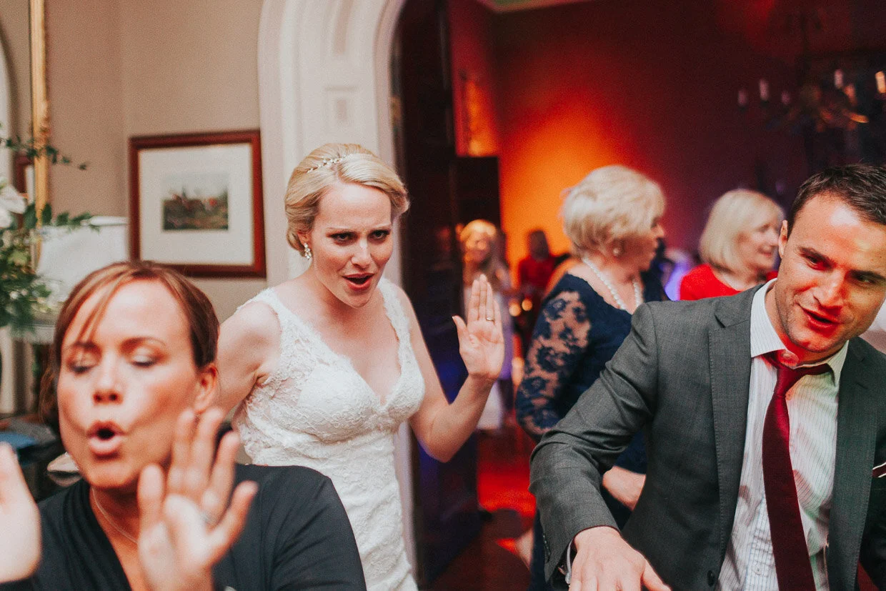 Bride and guests dancing at the reception in the main house Wedding couple dancing, facing each other for their first dance in between spotlights on the Ballynatray Estate for a Cork Wedding
