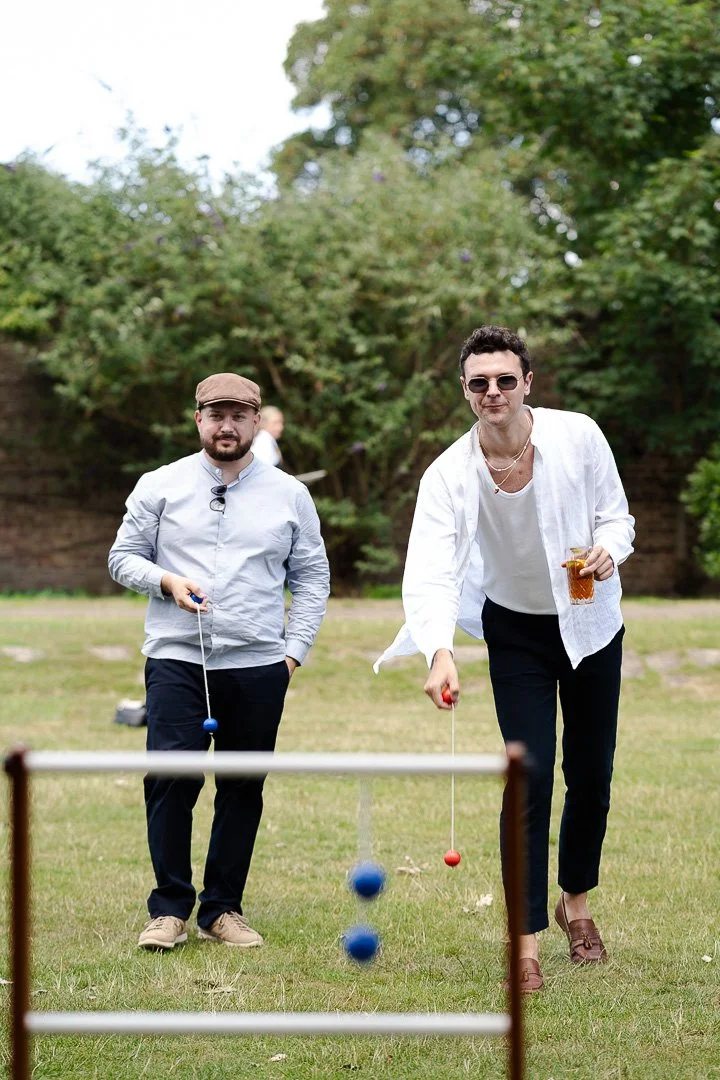 Two guests playing a lawn game called Ladder Toss at a Hampton Court House Wedding.