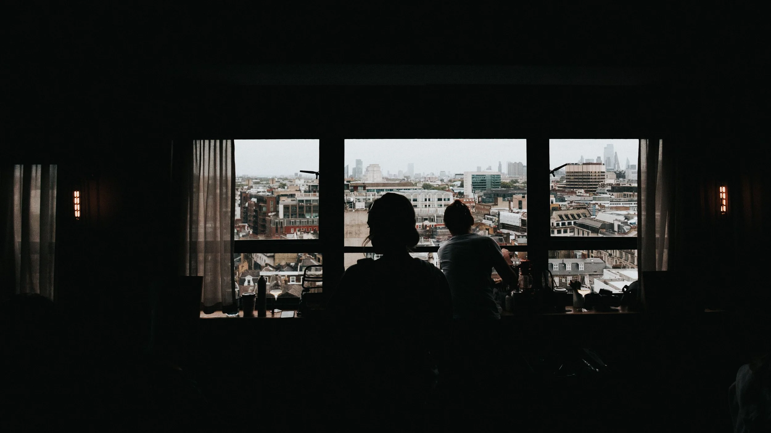 The silhouette of a bride sitting in front of a window showing the landscape of London