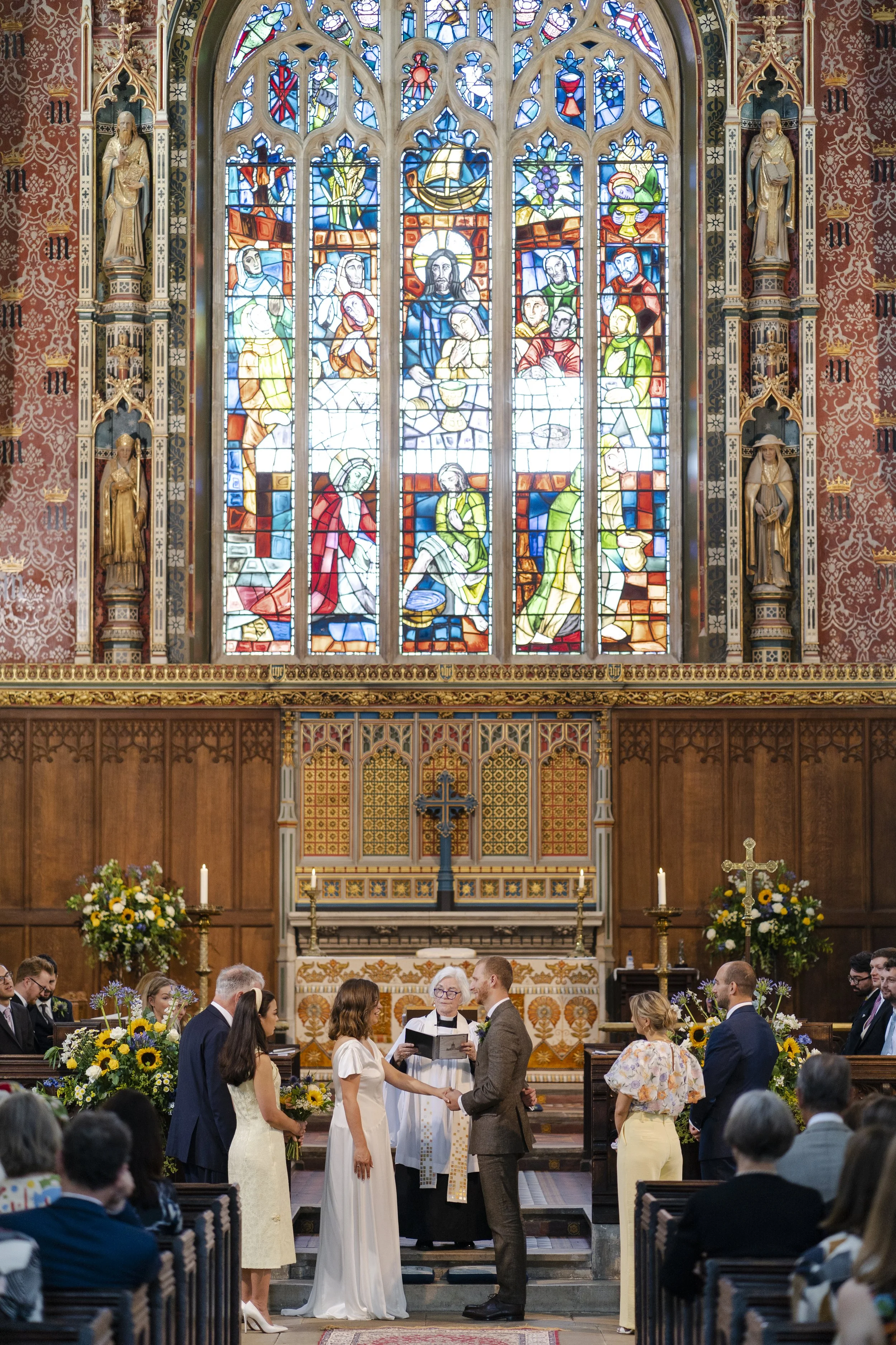 Wedding couple at front of St Michael's Church under the main stained glass window facing each other at a Highgate, London Wedding