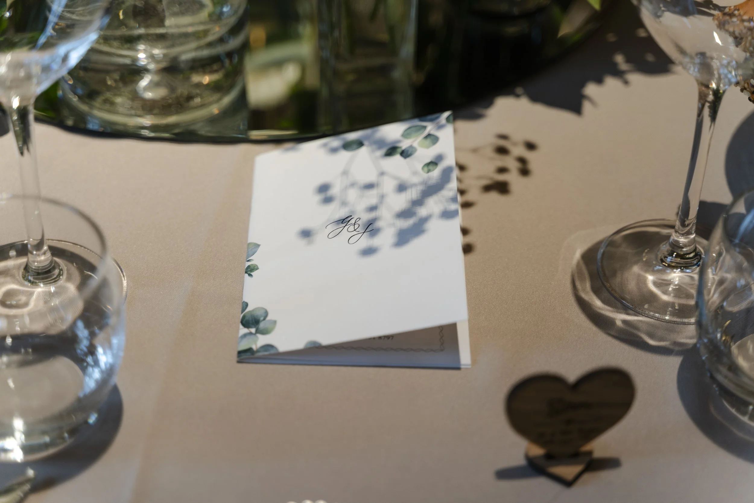 An invitation on a table with harsh shadows coming from some flowers in a vase at a Micklefield Hall Wedding