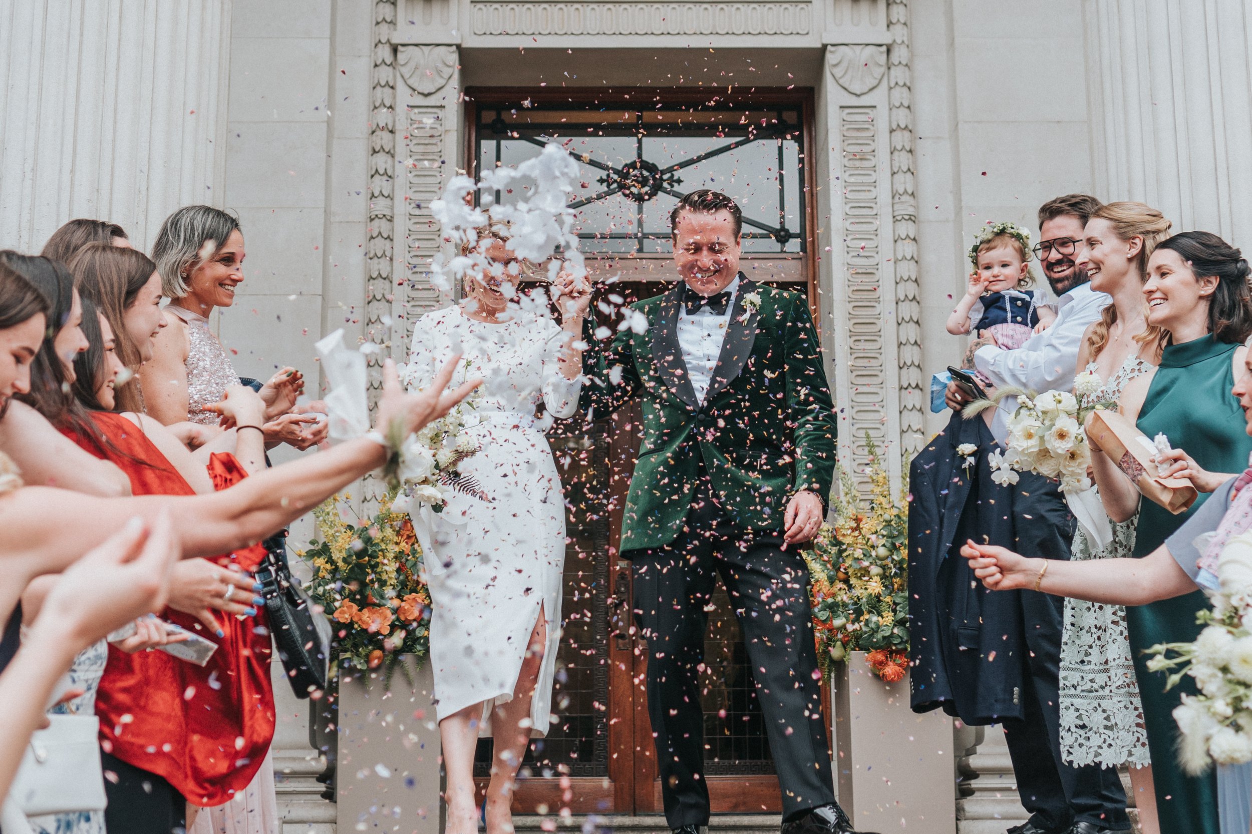 Wedding couple at the top of the steps at Old Marylebone Town Hall getting showered with Confetti