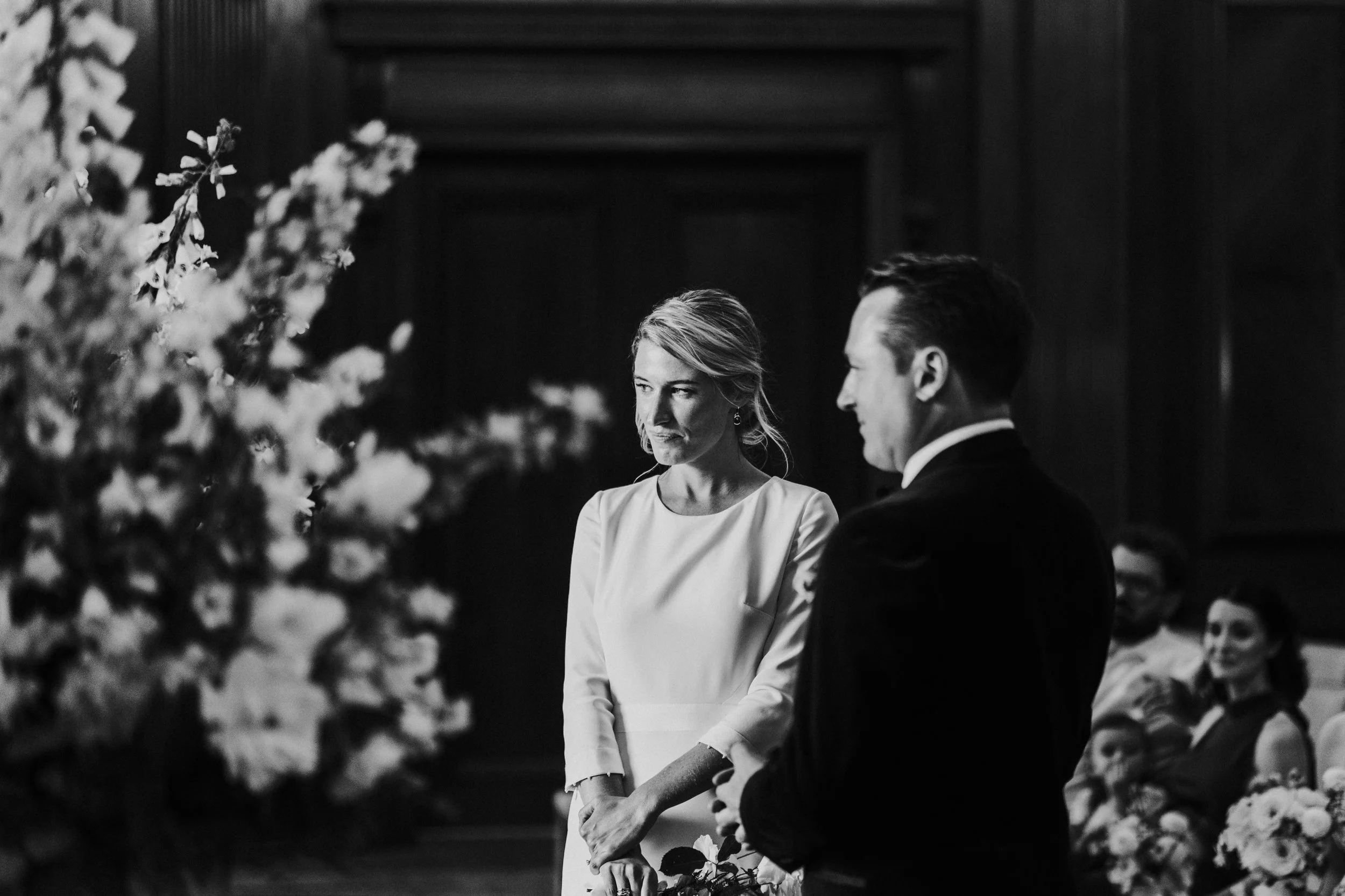 Wedding couple at the front of the ceremony room with the bride in focus at a Old Marylebone Town Hall Wedding
