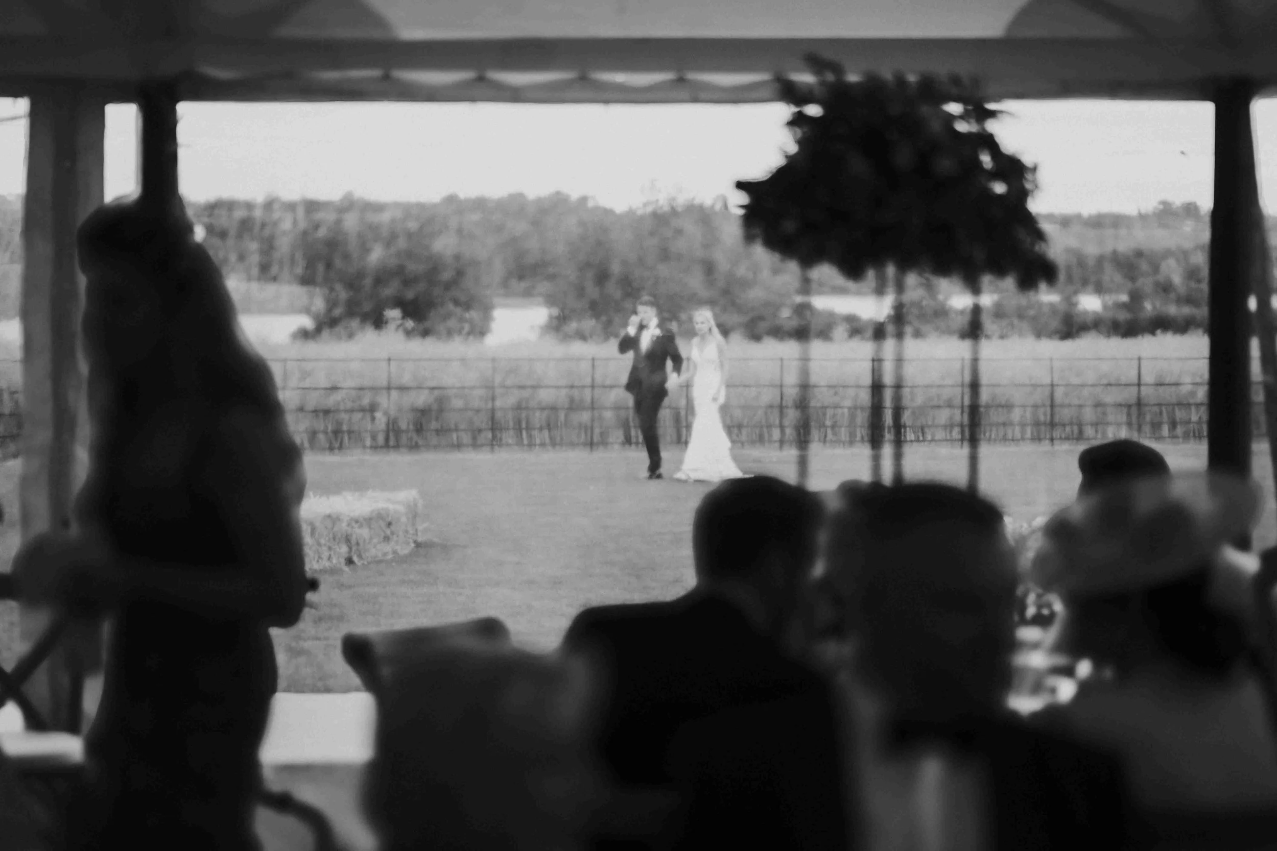 Couple in the background, while guests mingle in the wedding reception marquee at the Halfmoon Farm Wedding in Rutland
