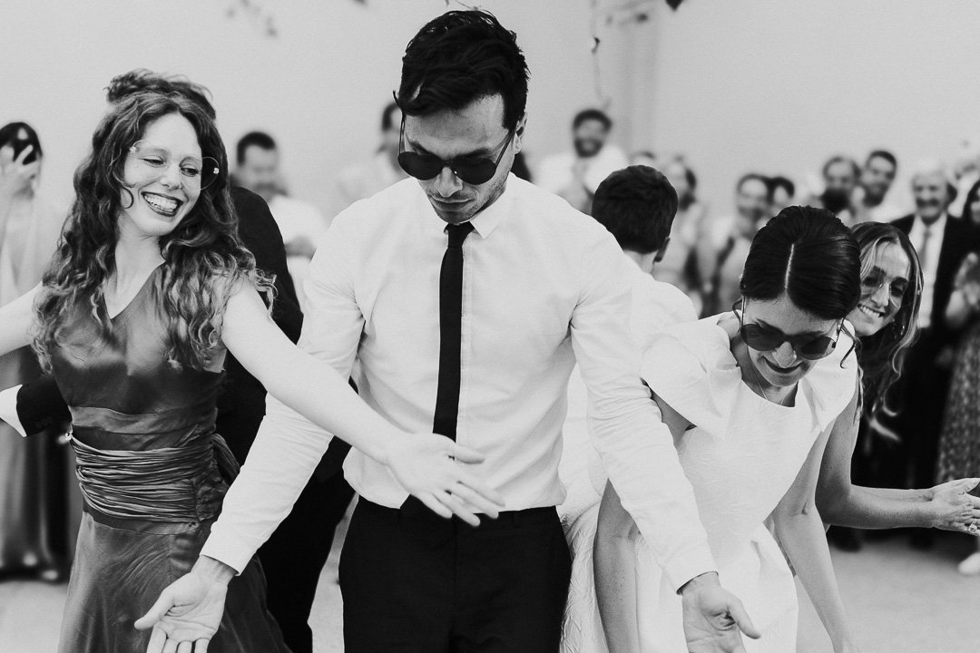 Wedding guest and bride wearing heart-shaped sunglasses performing a dance routine in front of other guests on the dancefloor at a Hampton Court House Wedding.