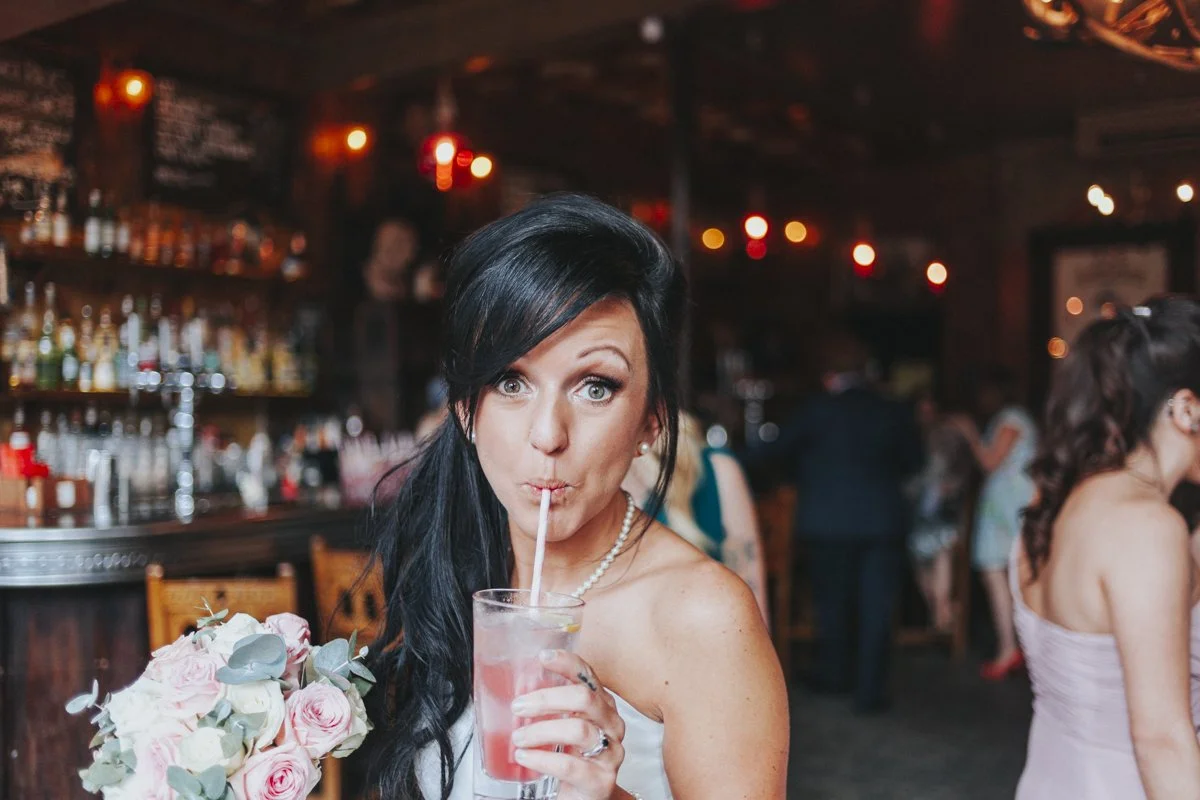 Bride drinking a cocktail by the bar at the iconic The Old Queens Head pub, Essex Road, Islington for a London Wedding