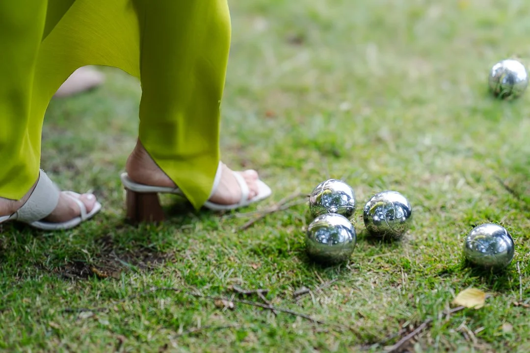 Five croquet balls on the lawn with a guest shoes next to the balls in the shot at a Hampton Court House Wedding.