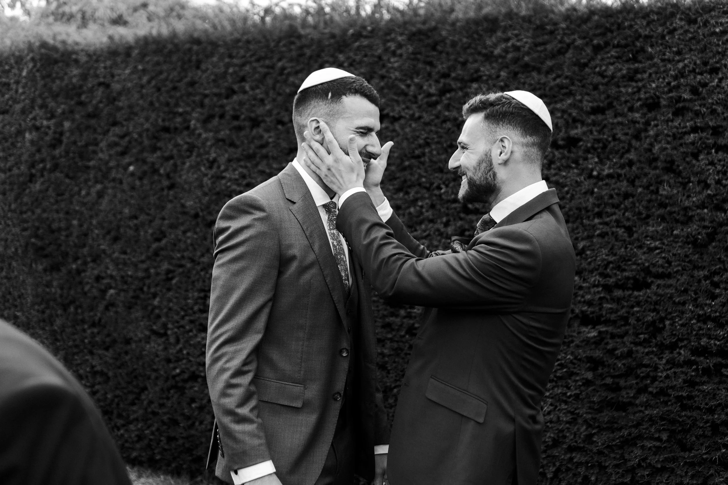 Guest holding groom face in his hands smiling at him at a Micklefield Hall Wedding
