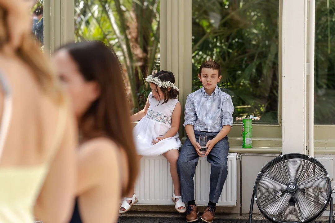 Flower girl and young guest sitting on the windowsill with a tube of Pringles next to them at a Hampton Court Wedding.