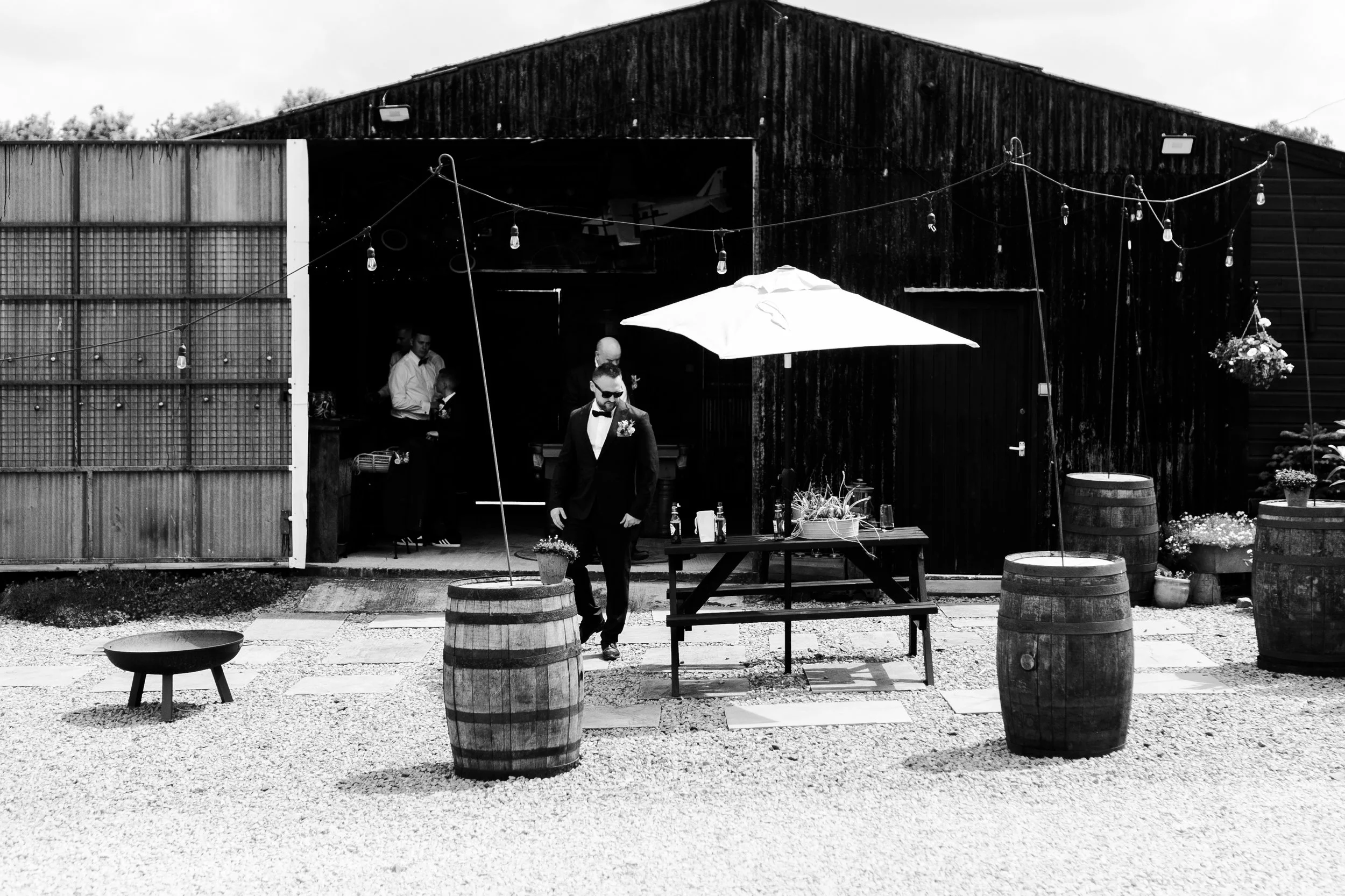 A guest outside the barn with barrels set up as tables at a rhyse farm wedding