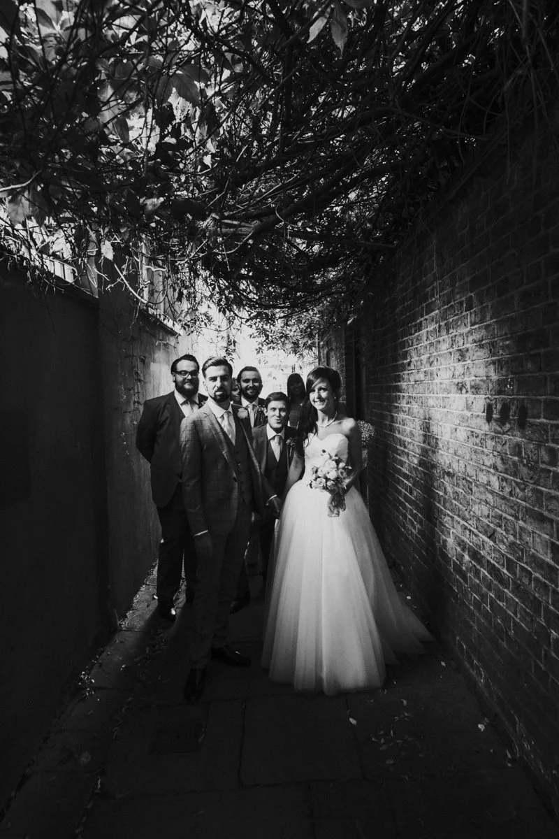 Bridal party with the Bride & Groom in the front posing in a alleyway near Islington Town Hall Wedding Venue