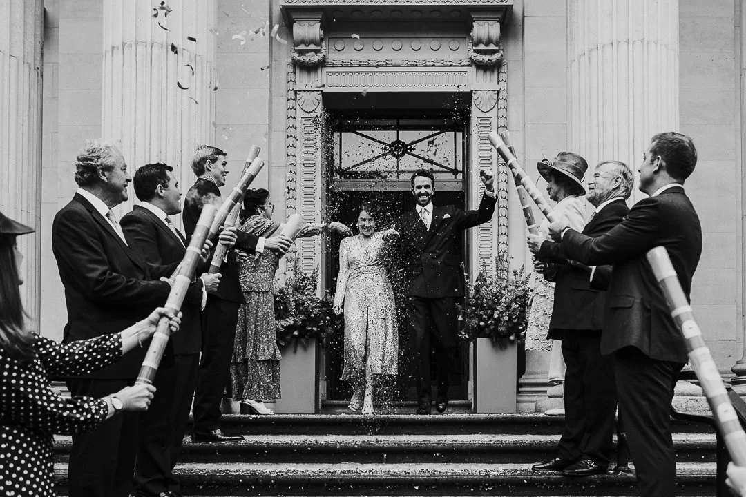 Wedding couple walking outside while a confetti line with the guests are waiting at the Old Marylebone Town Hall Wedding.