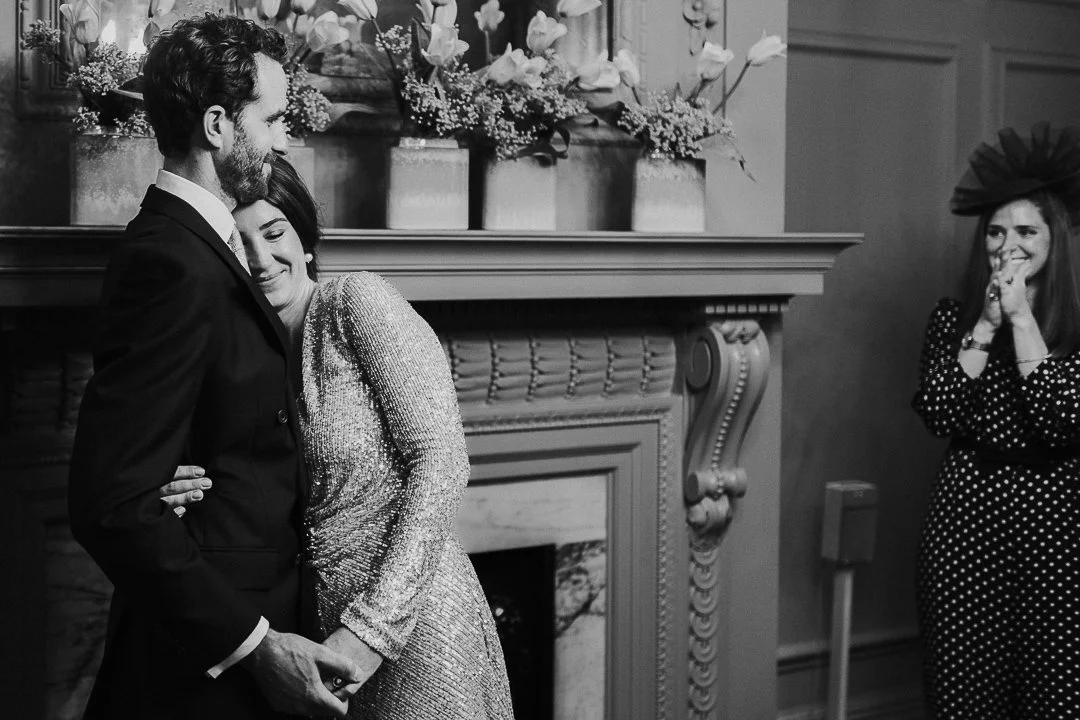 Bride hugging the Groom very closely just after vowels in the ceremony room at the Old Marylebone Town Hall.