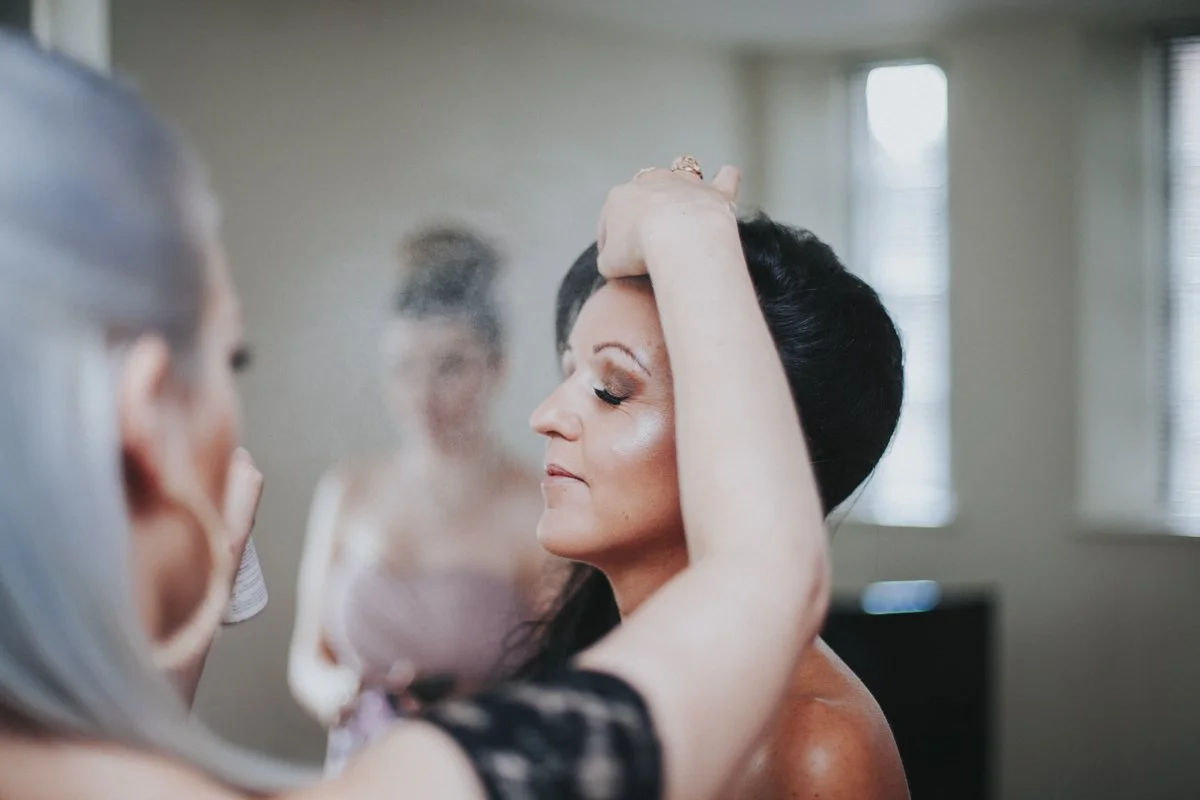 The bride with her eyes closed while her bridesmaids applies Hairspray before her Islington Town Hall Wedding