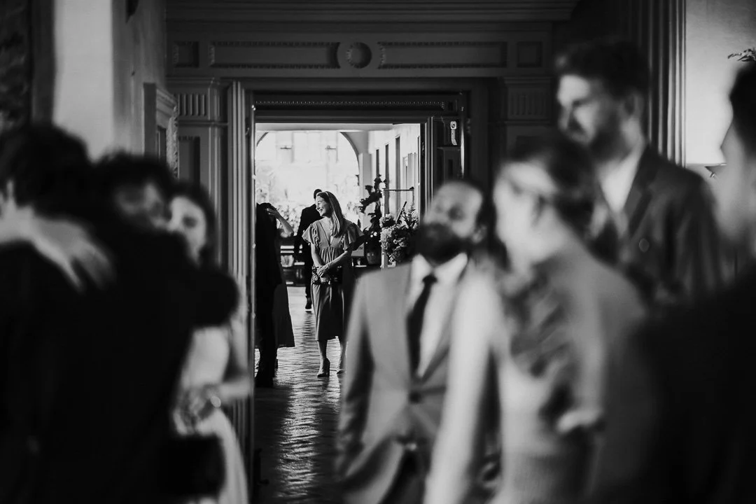 A view of a guest in the open doorway of the Glasshouse convservatory with other guest blurred in the forground of the image at a Hampton Court House Wedding