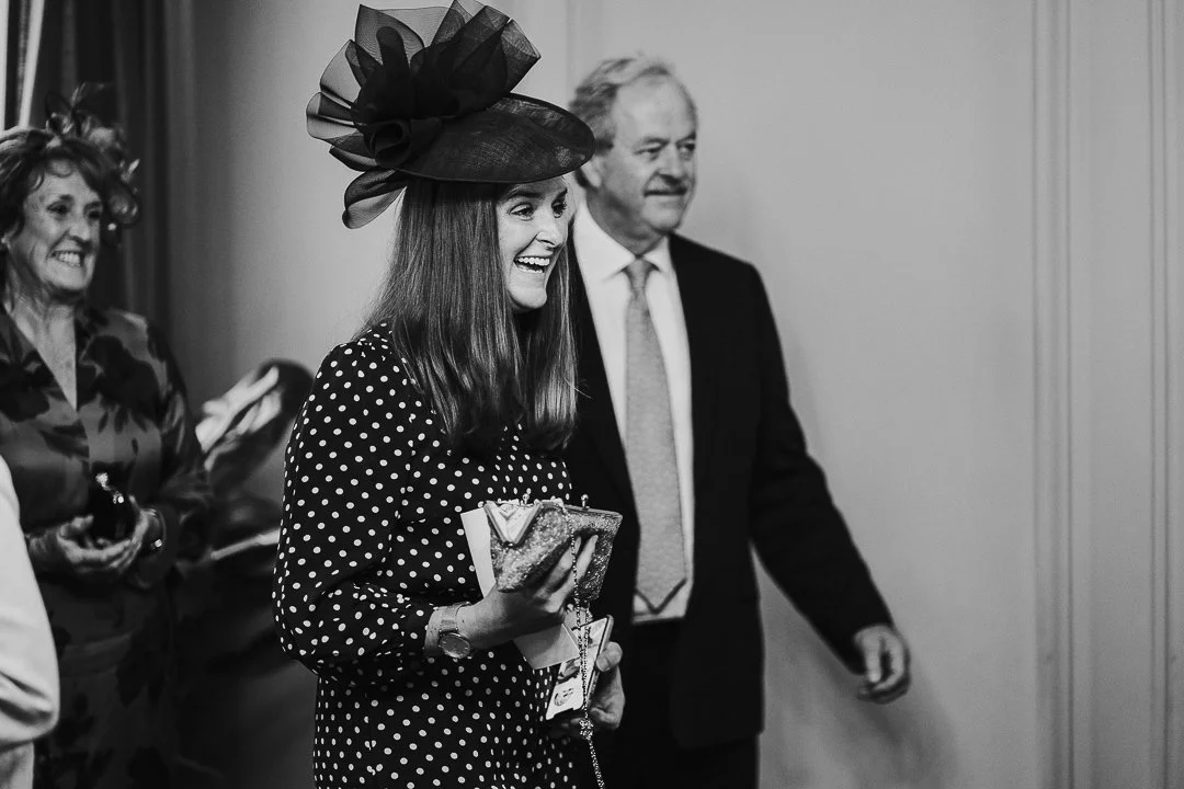 Groom's sister smiling at a guest out of the shot in the ceremony room at the Old Marylebone Town Hall Wedding
