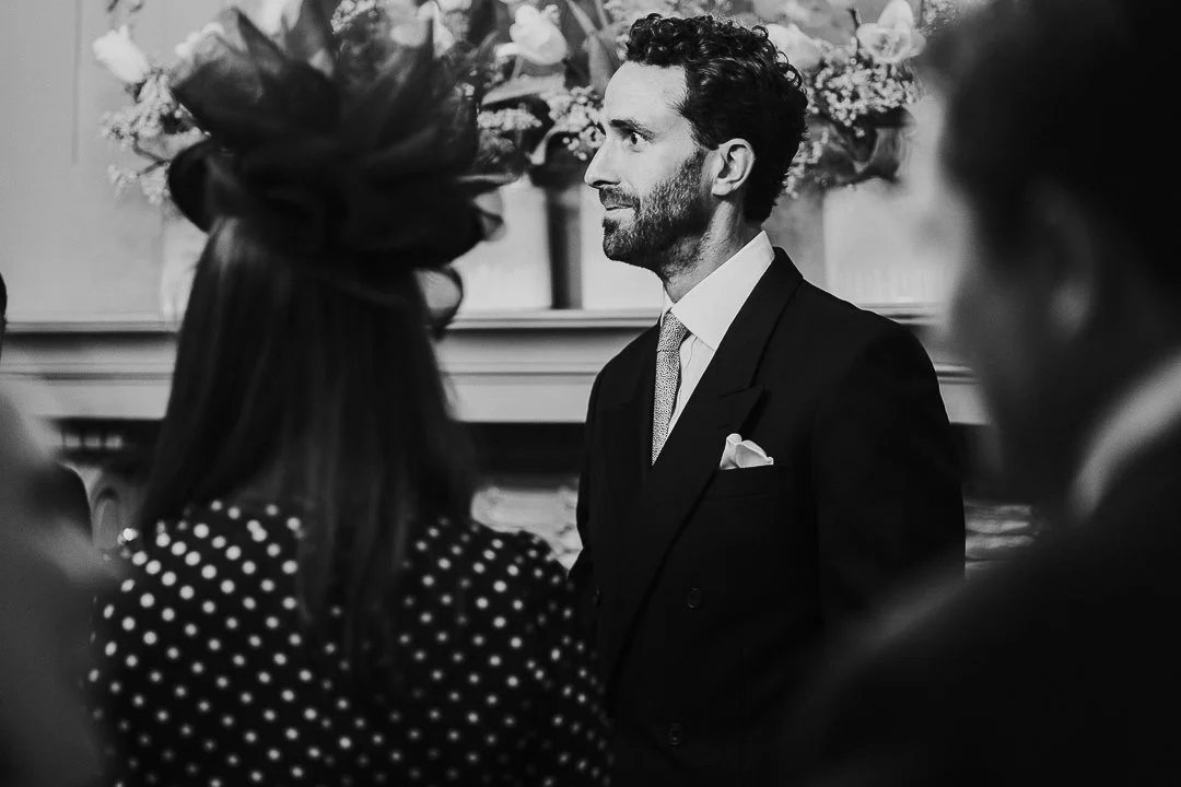 Groom looking surprisingly shocked while the bride enters the ceremony room at the Old Marylebone Town Hall Wedding.